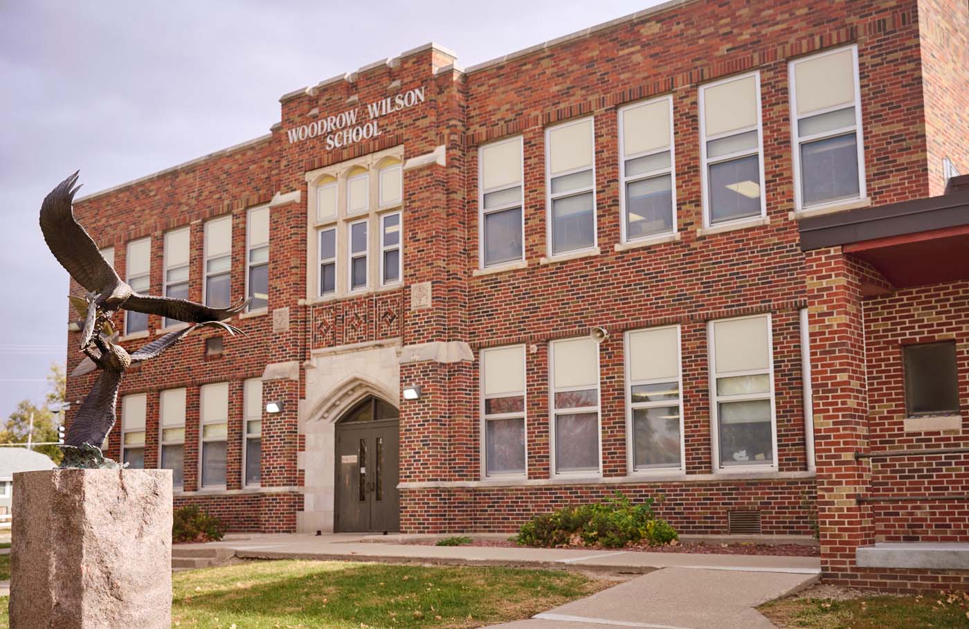 Exterior of a brick building, with a paved walkway leading to a door