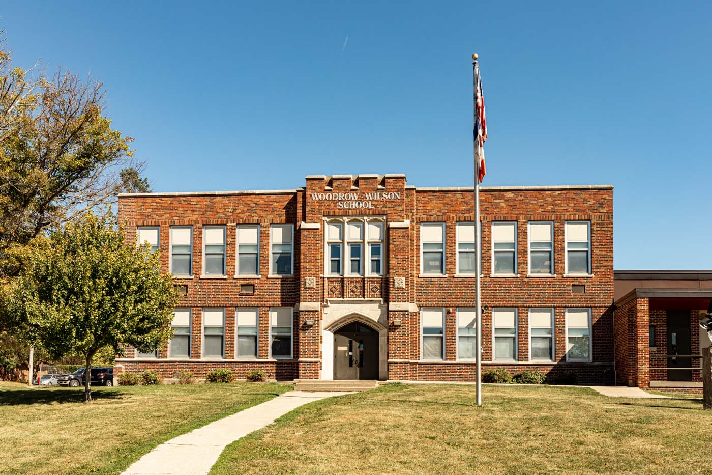 Exterior of a brick building, with a paved walkway leading to a door