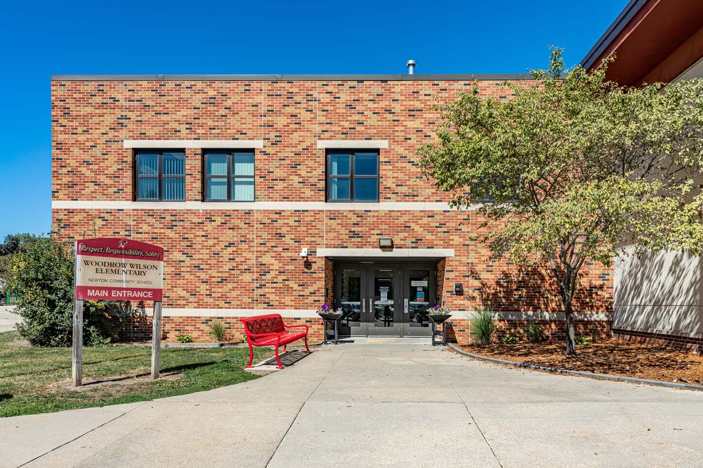 Exterior of a brick building, with a paved walkway leading to a door