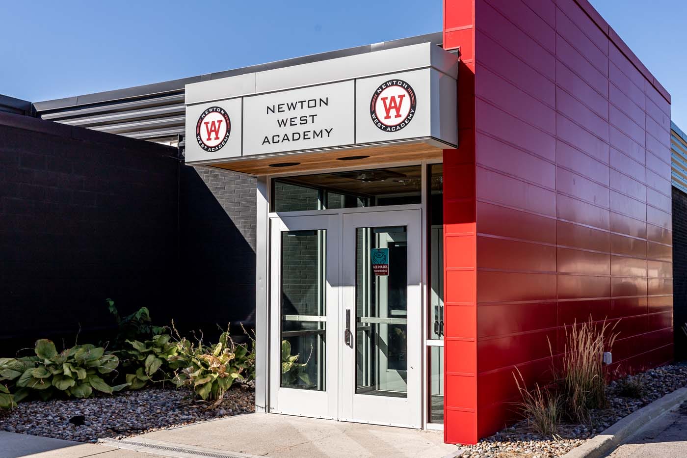 Exterior of WEST Academy, a building that is modern, with grey and red exterior coloring.