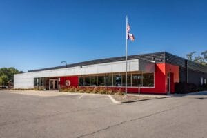 Exterior of WEST Academy, a building that is modern, with grey and red exterior coloring.