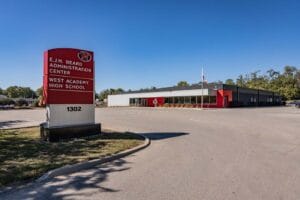 Exterior of WEST Academy, a building that is modern, with grey and red exterior coloring.