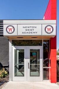 Exterior of WEST Academy, a building that is modern, with grey and red exterior coloring.