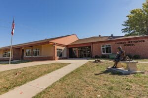 Exterior of a brick building, with a paved path leading to a door.