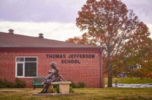 Exterior of a brick building, with a paved path leading to a door.