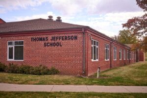 Exterior of a brick building, with a paved path leading to a door.