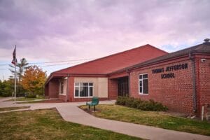 Exterior of a brick building, with a paved path leading to a door.