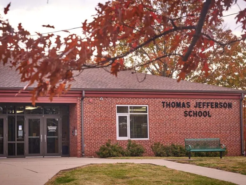 Exterior of a brick building, with a paved path leading to a door.