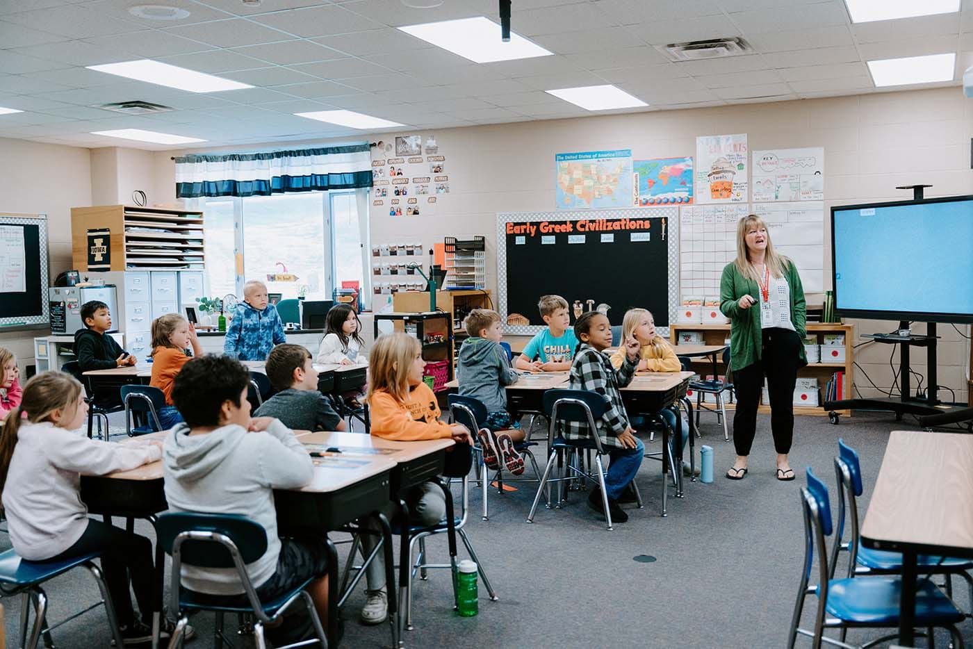 Students in classroom, sitting either on the floor or in a chair, participating in classroom activities