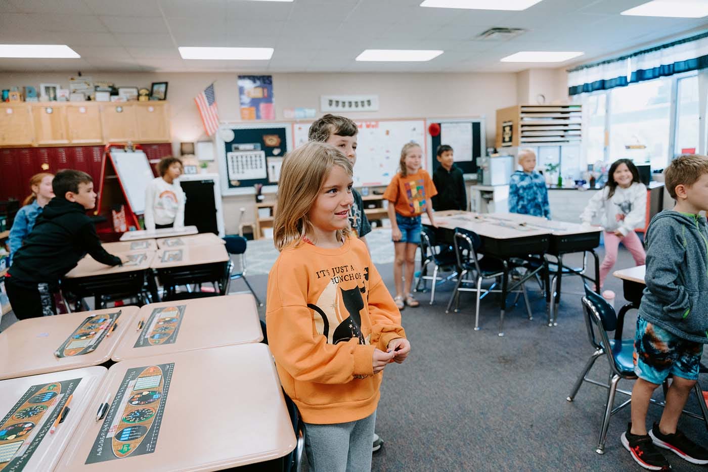 Students in classroom, sitting either on the floor or in a chair, participating in classroom activities