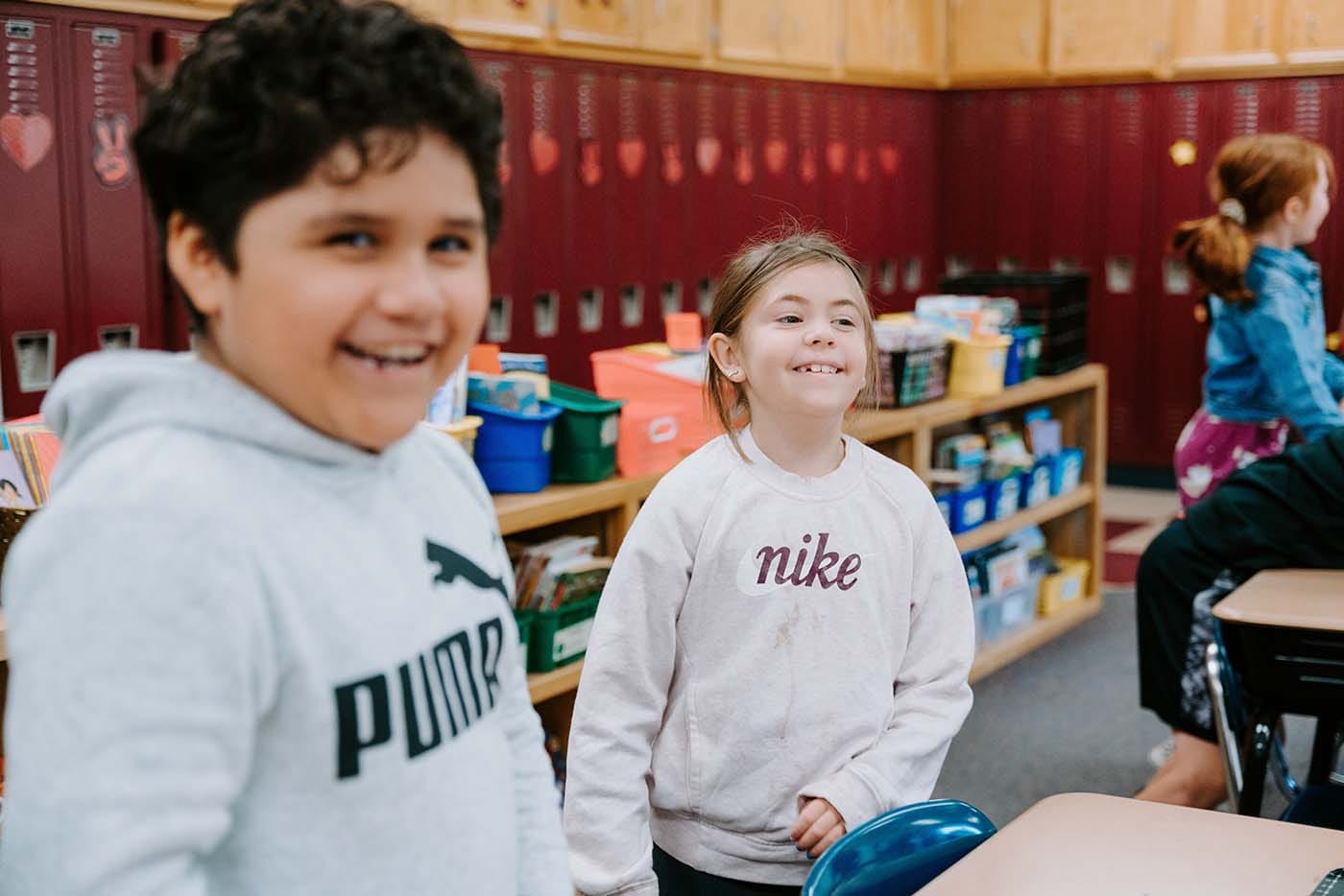 Students in classroom, sitting either on the floor or in a chair, participating in classroom activities